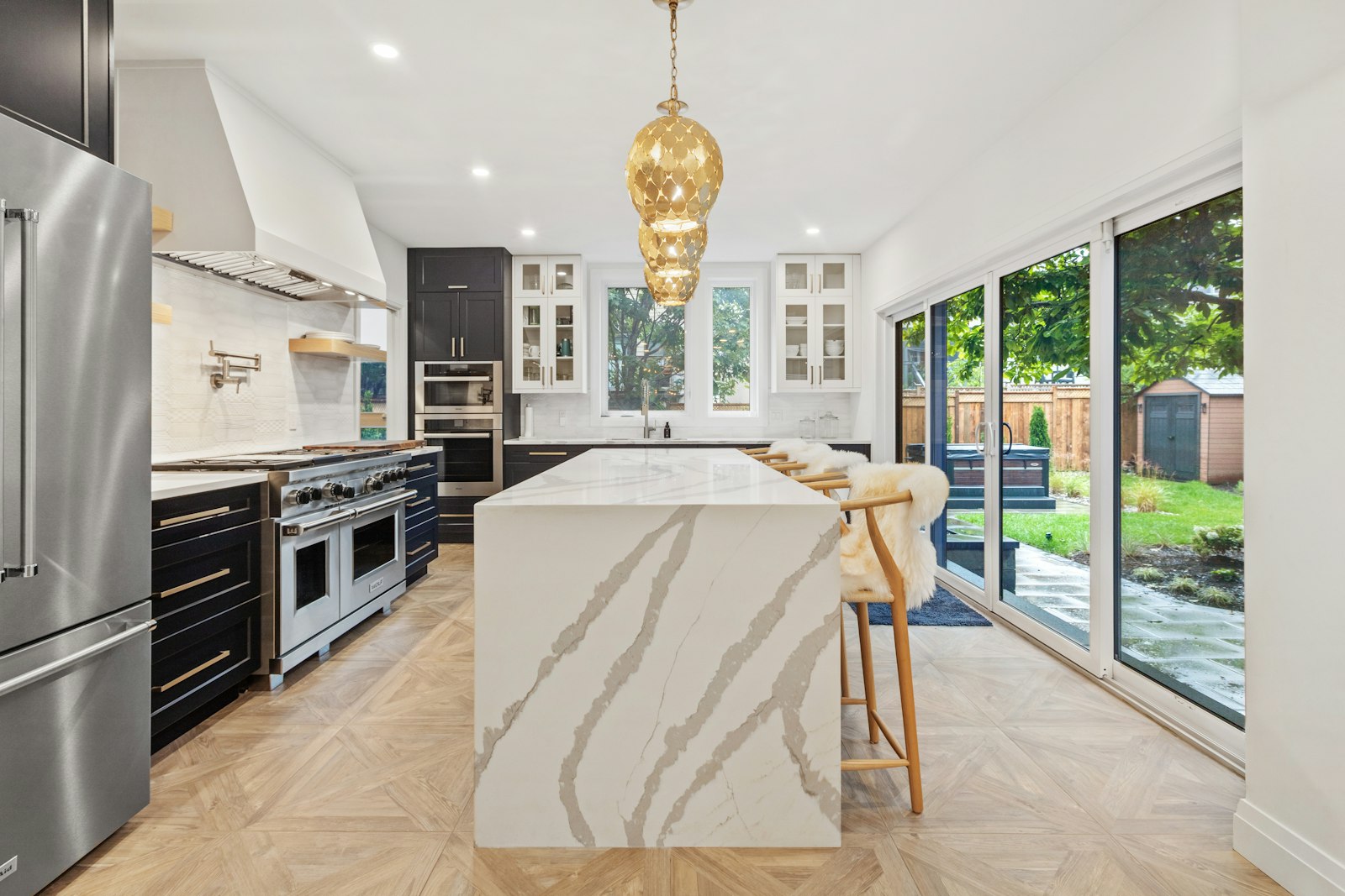 Cocina de alta gama con frentes en madera, isla y encimera de piedra natural en un piso de Barcelona